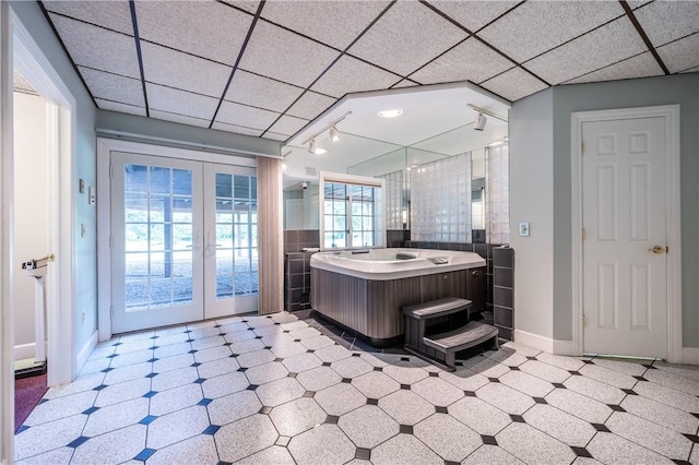 bathroom with french doors, a paneled ceiling, track lighting, baseboards, and tile patterned floors