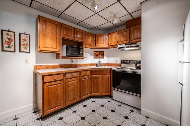 kitchen with range with electric stovetop, light countertops, a sink, black microwave, and under cabinet range hood