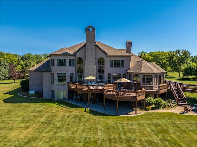 rear view of property with a chimney, a deck, and a yard