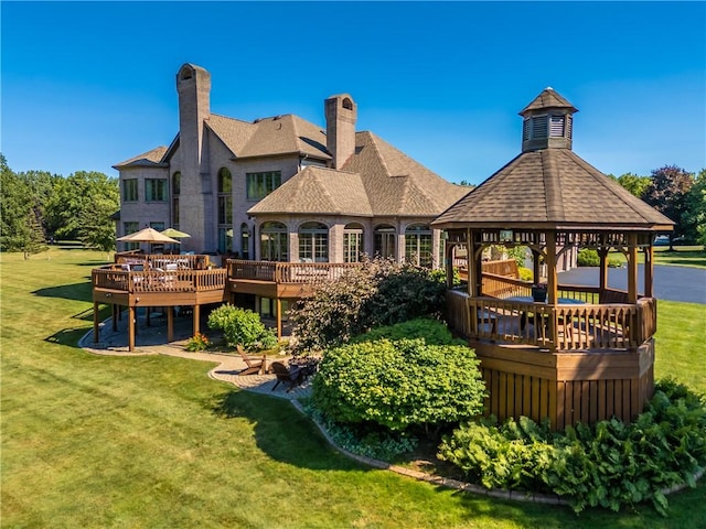 rear view of house with a deck, a lawn, and a gazebo