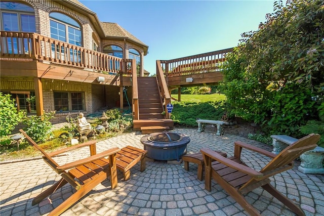 view of patio / terrace with an outdoor fire pit, stairs, and a deck