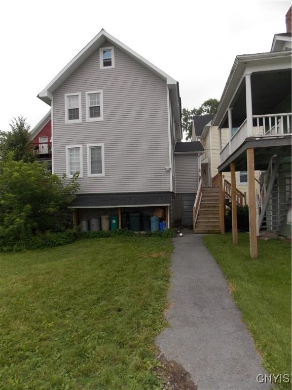 view of side of home with stairway and a lawn