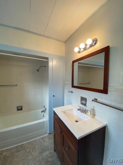 full bathroom with shower / bathing tub combination, vanity, and tile walls