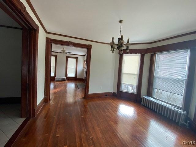 unfurnished dining area with baseboards, crown molding, radiator heating unit, and wood finished floors