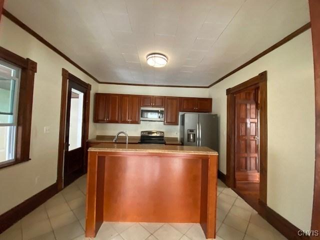 kitchen with appliances with stainless steel finishes, a sink, baseboards, and ornamental molding