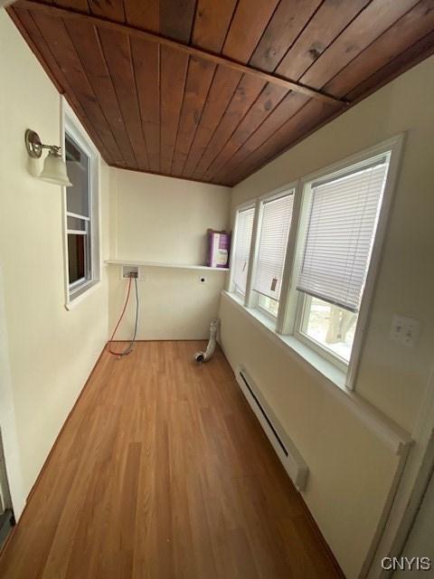 laundry room featuring light wood-type flooring, wooden ceiling, a baseboard radiator, and laundry area