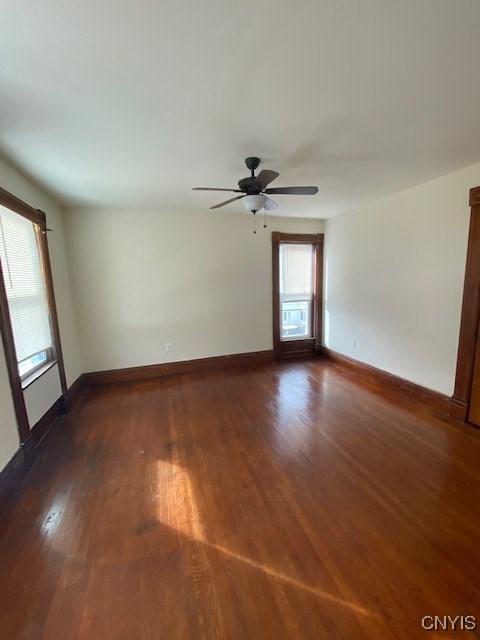 spare room with dark wood finished floors, baseboards, and ceiling fan