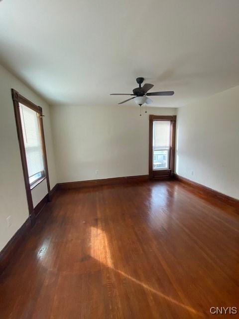 spare room featuring dark wood-type flooring, baseboards, and a ceiling fan