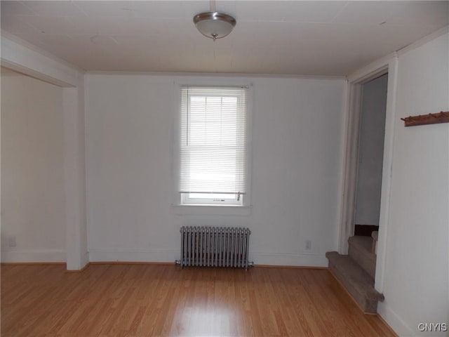 spare room featuring baseboards, light wood-style floors, and radiator