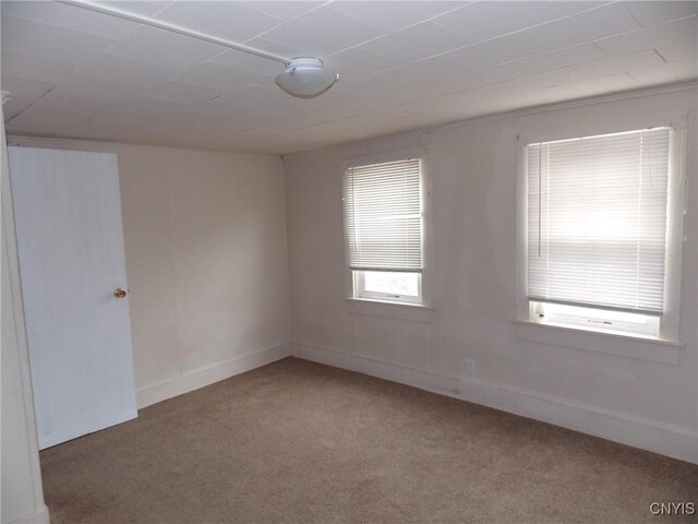 empty room featuring carpet and baseboards