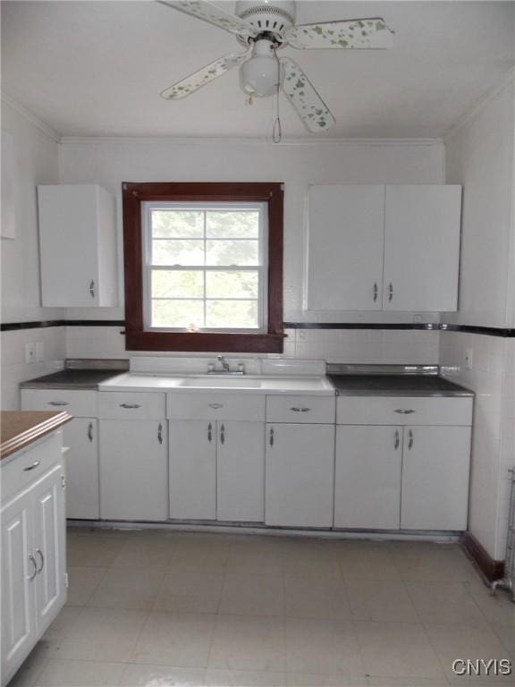 kitchen with ceiling fan, ornamental molding, white cabinets, and backsplash