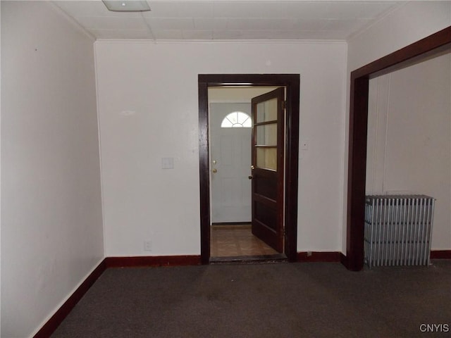 carpeted empty room featuring ornamental molding, radiator, and baseboards