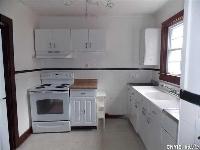 kitchen featuring under cabinet range hood, white electric range oven, white cabinets, and a sink