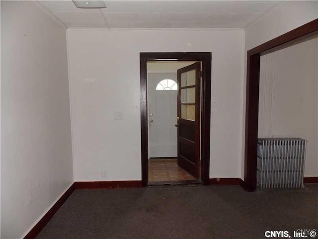 carpeted spare room featuring radiator and baseboards