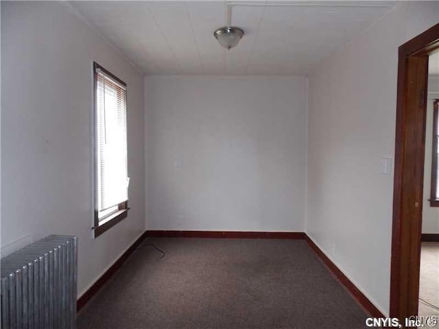 carpeted empty room featuring radiator heating unit and baseboards