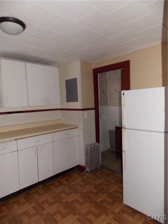 kitchen featuring freestanding refrigerator, electric panel, radiator heating unit, and wallpapered walls