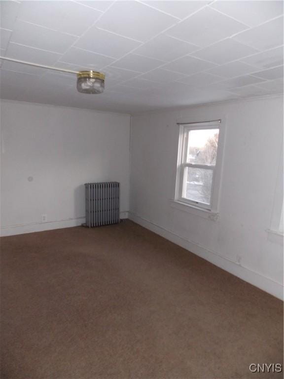 empty room with baseboards, carpet flooring, and radiator