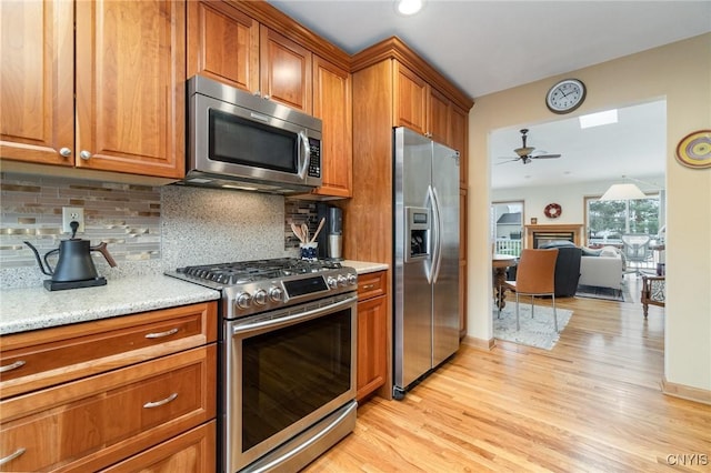 kitchen featuring brown cabinetry, a fireplace, and stainless steel appliances