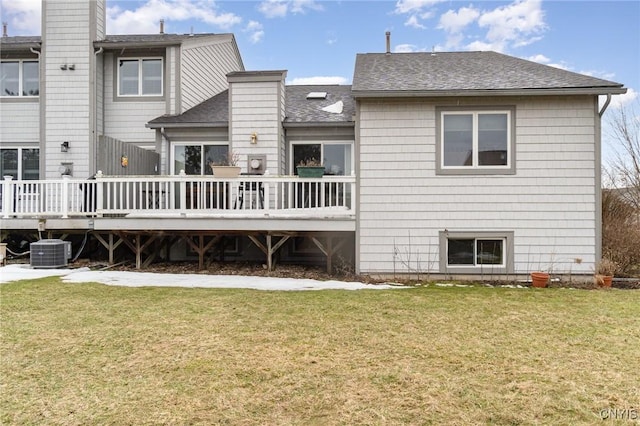 rear view of house with a shingled roof, a lawn, a wooden deck, and central air condition unit