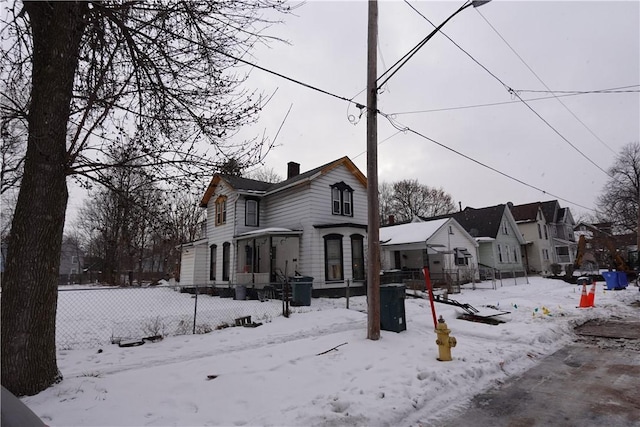 view of front of home with a garage, a residential view, a chimney, and fence