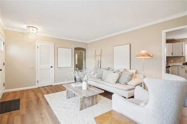 living area featuring ornamental molding, arched walkways, and light wood finished floors