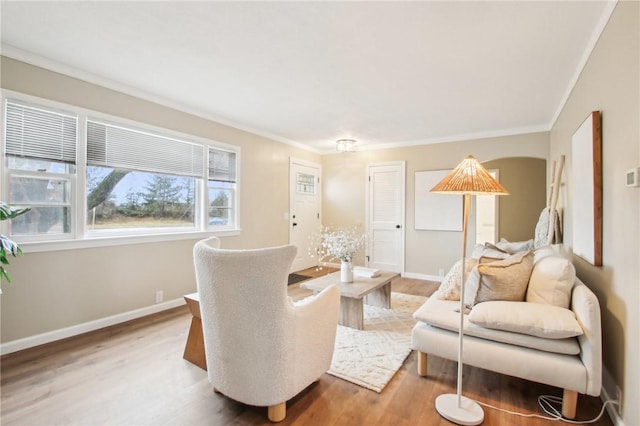 living area with light wood-style floors, crown molding, and baseboards