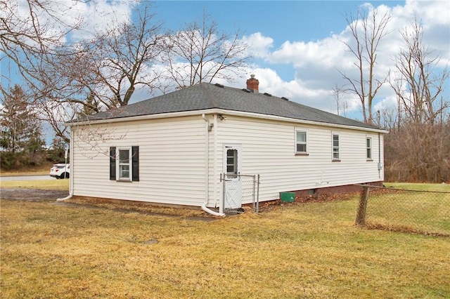 view of side of property with roof with shingles, a lawn, a chimney, and fence