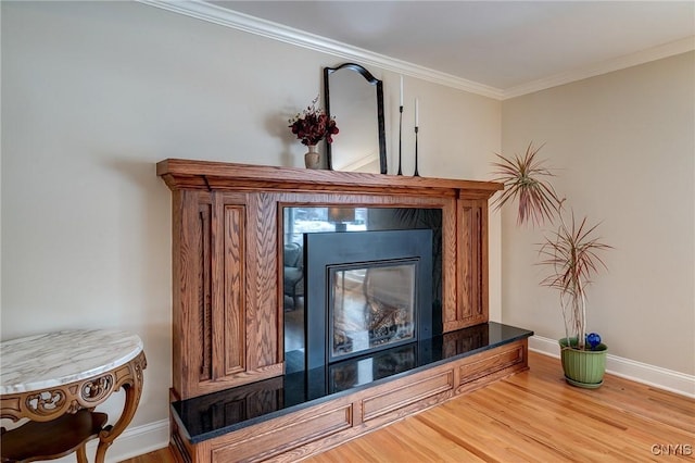 room details with crown molding, baseboards, wood finished floors, and a glass covered fireplace