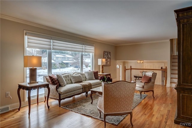 living room with ornamental molding, light wood-type flooring, and visible vents