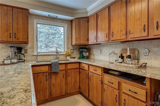 kitchen featuring tasteful backsplash, ornamental molding, a sink, and brown cabinets