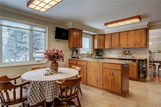 kitchen featuring a peninsula, light countertops, ornamental molding, backsplash, and brown cabinets