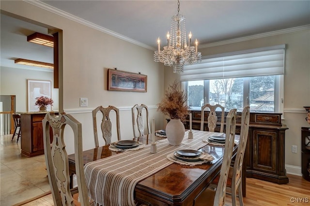 dining room with ornamental molding, a notable chandelier, and light wood-style floors