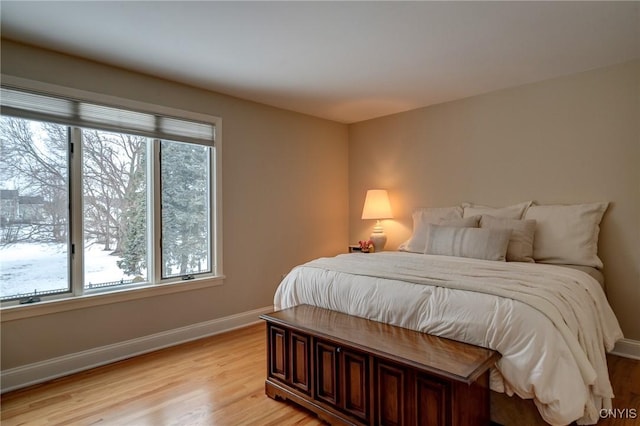 bedroom featuring baseboards, multiple windows, and light wood-style floors