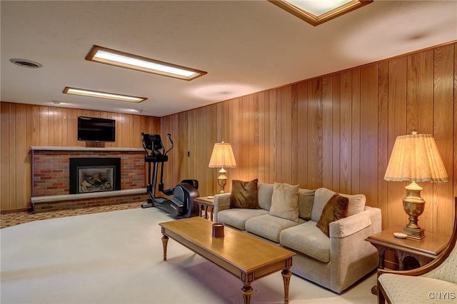 carpeted living room featuring wood walls, a fireplace, and visible vents