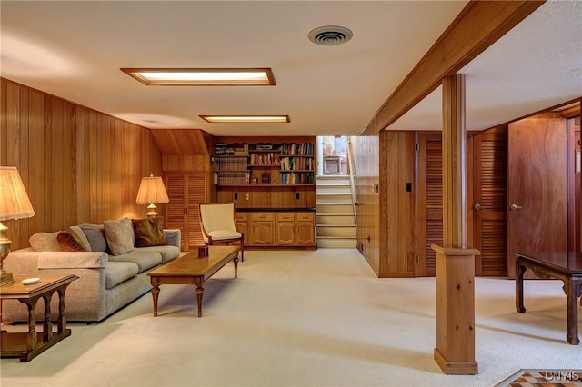 living area with wood walls, visible vents, and light colored carpet