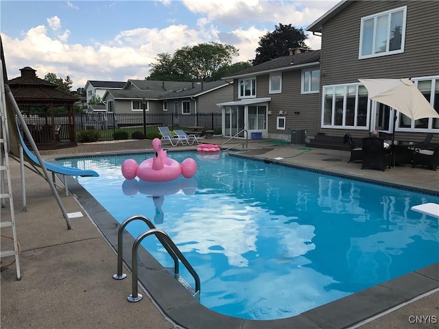 view of swimming pool with a fenced in pool, fence, a water slide, and a patio