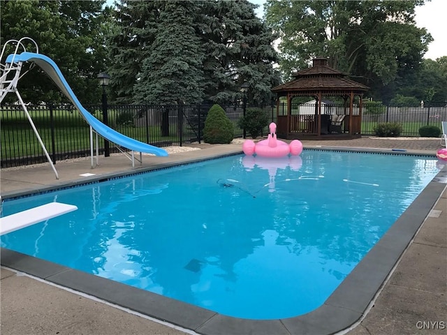 view of swimming pool with a fenced in pool, a water slide, fence, and a gazebo