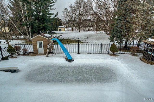 snowy yard with a shed, an outdoor structure, and fence