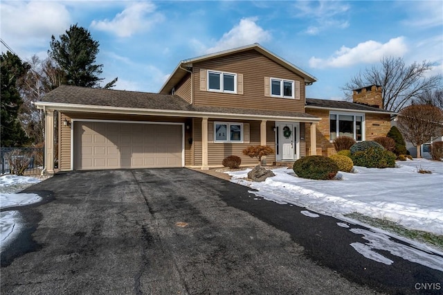 view of front of house with a garage, driveway, a chimney, and fence