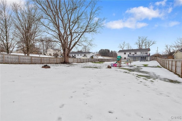 snowy yard with a fenced backyard and a playground