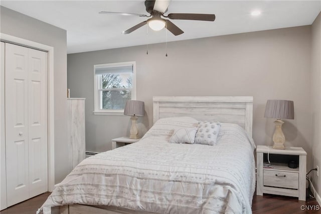 bedroom featuring ceiling fan, a closet, baseboard heating, and wood finished floors