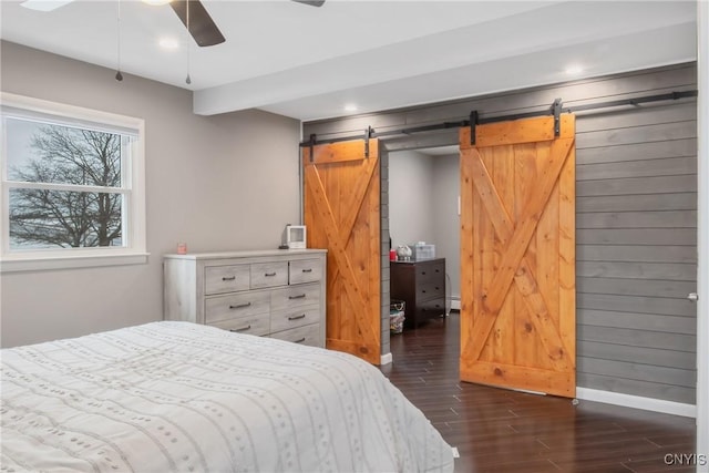 bedroom featuring a barn door, baseboards, a ceiling fan, dark wood-style floors, and baseboard heating