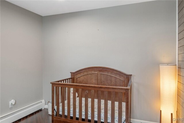 bedroom with a crib and a baseboard heating unit