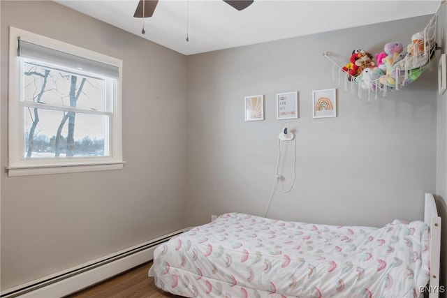 bedroom with ceiling fan, baseboard heating, and wood finished floors