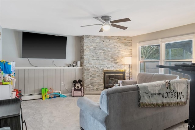 living room featuring a ceiling fan, wainscoting, carpet, a fireplace, and a baseboard heating unit