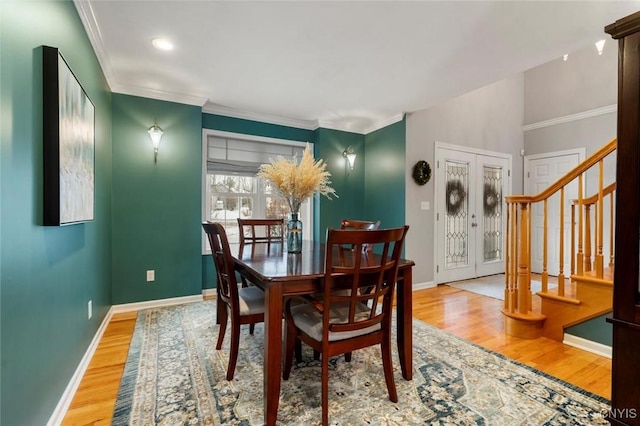 dining area featuring baseboards, stairs, ornamental molding, and wood finished floors