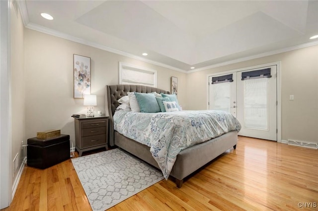 bedroom with a tray ceiling, french doors, crown molding, light wood-style flooring, and access to outside