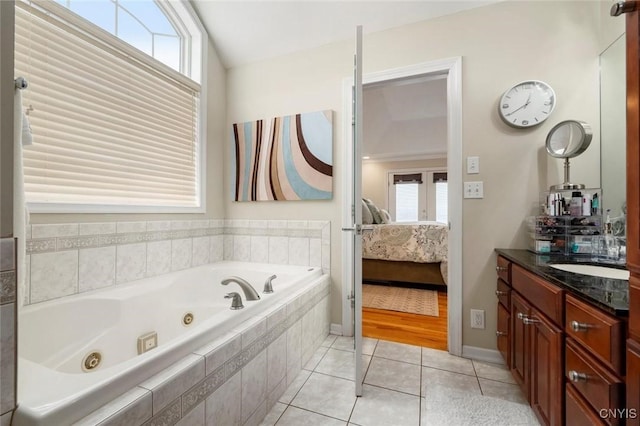 ensuite bathroom featuring lofted ceiling, a tub with jets, ensuite bathroom, tile patterned flooring, and vanity