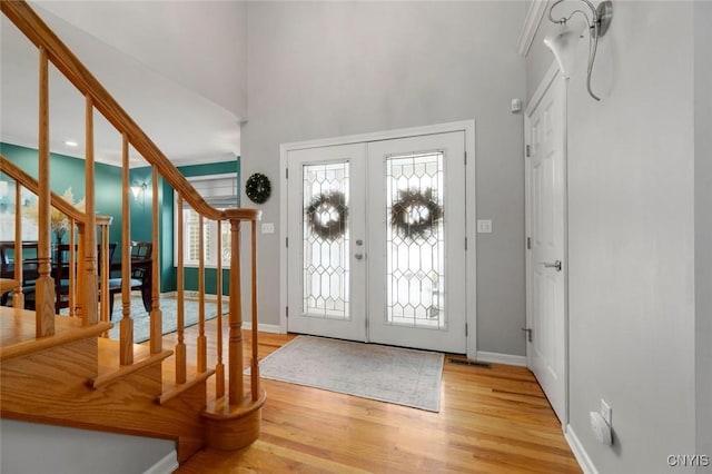 entrance foyer featuring french doors, visible vents, wood finished floors, baseboards, and stairs