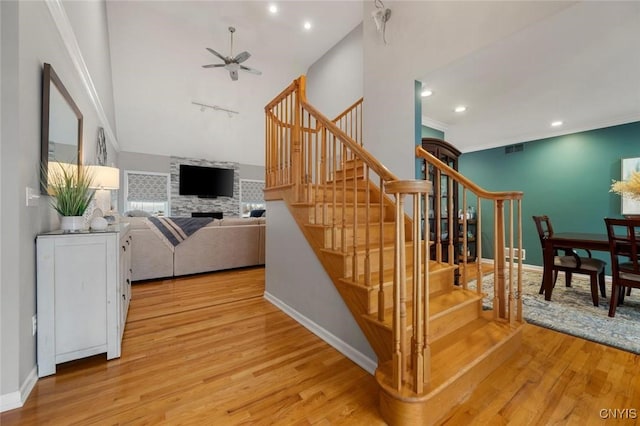 stairs featuring visible vents, crown molding, baseboards, and wood finished floors